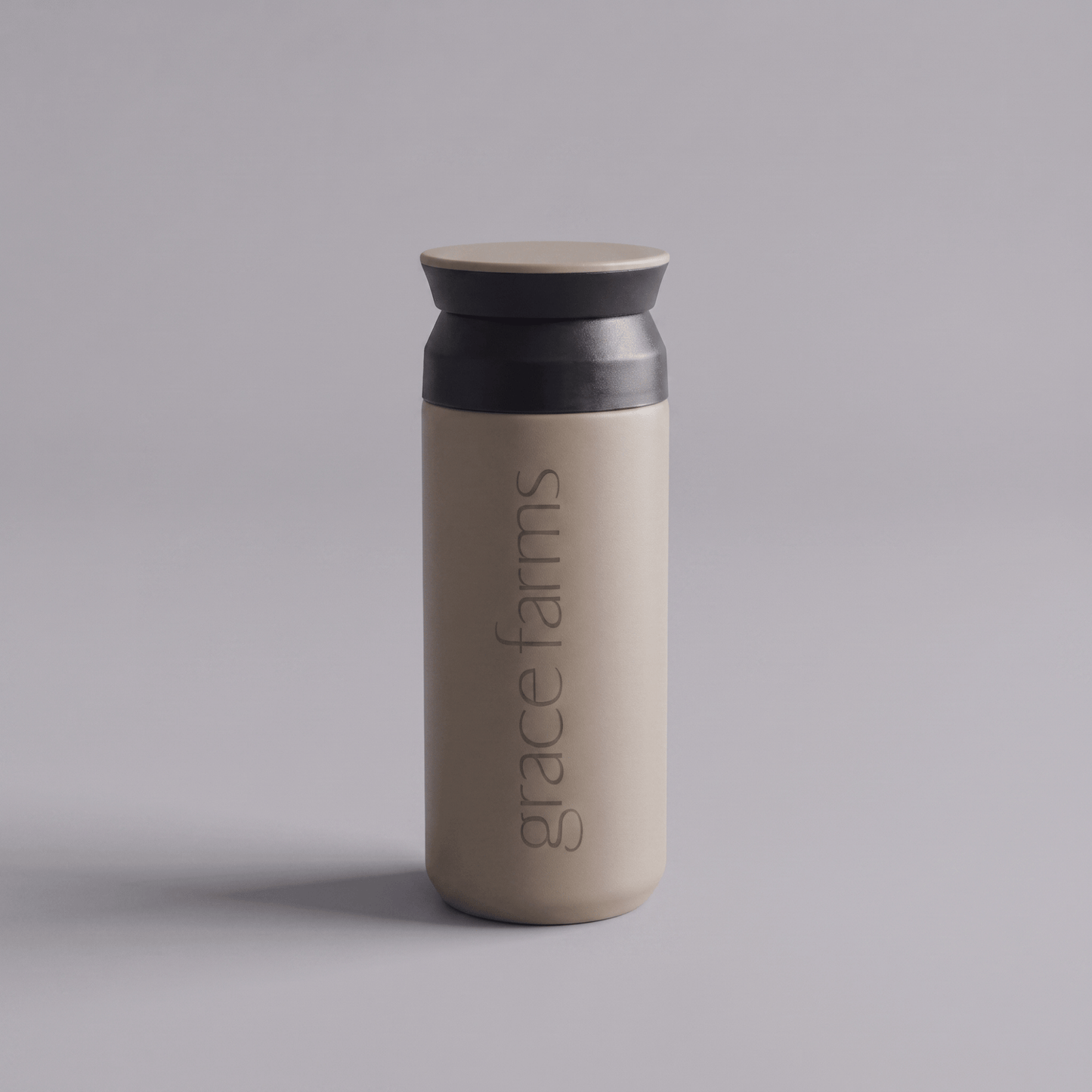 KINTO travel tumbler in sand beige, featuring the vertical white text 'grace farms' on the front, set against a solid gray background.