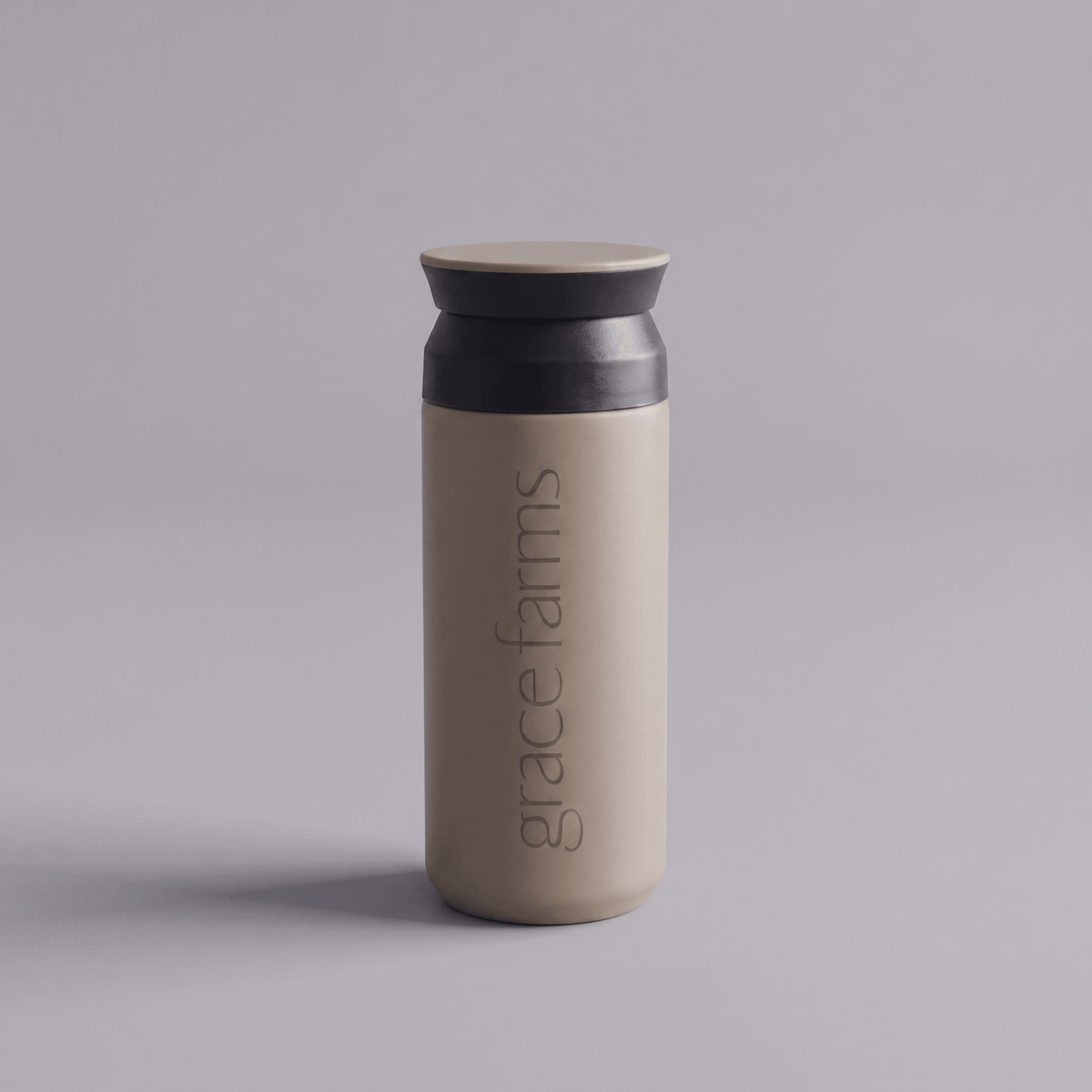 KINTO travel tumbler in sand beige, featuring the vertical white text 'grace farms' on the front, set against a solid gray background.